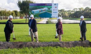 Four people in hardhats with shovels at the site of the new Palmer Florida building.