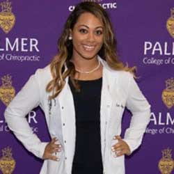 Remi Jeffries, Palmer Florida student, in white clinic coat in front of Palmer logo background.