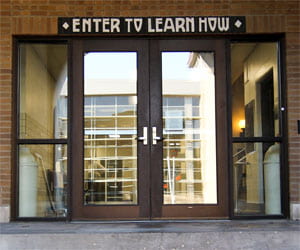double doors with a sign "enter to learn how" above entrance