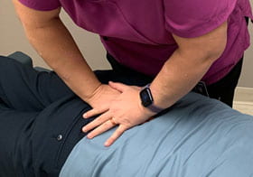 chiropractor's hands adjusting a patient's lower back.
