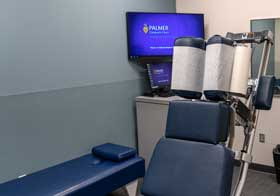 Office with chiropractic table, computer screen, and adjustment table.