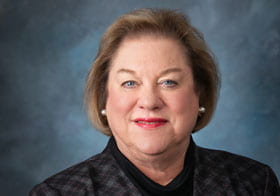 Vickie Anne Palmer headshot with Dave Palmer pin on lapel.