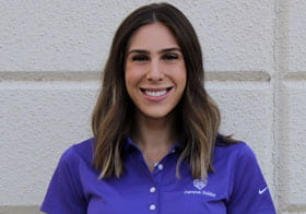 Gabby Giordano, Palmer West student, smiling in purple clinic polo.