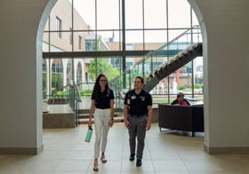 two students walking under the David D. Palmer Learning Commons arches.