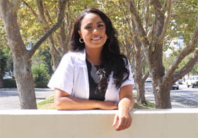 Naomi Velado-Tsegaye behind Palmer Chiropractic Clinics sign