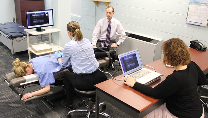 Three Palmer chiropractic researchers observing patient's low back.