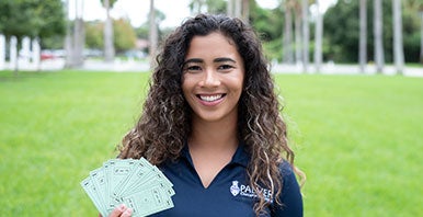 Student on college campus holding cards.