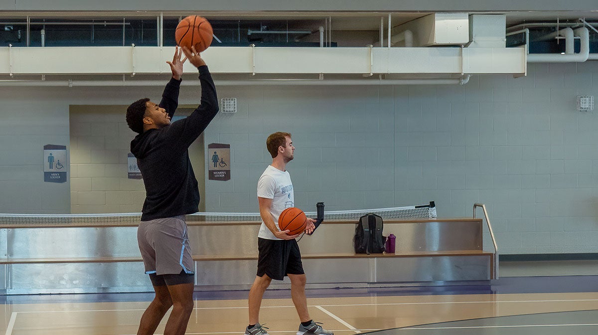 Two male students playing basketball.