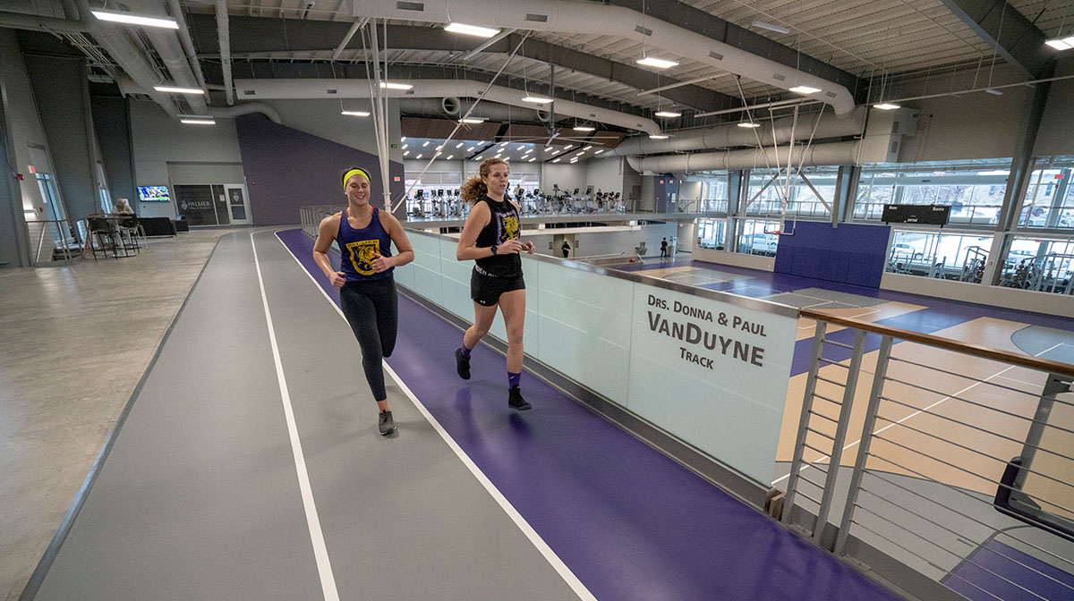 Two Palmer students running on purple track.