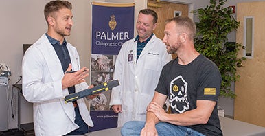 Chiropractor and student intern talking with a patient