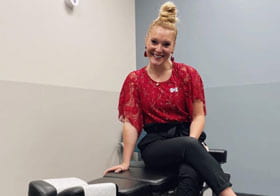 Kelsey Arneson, Palmer College of Chiropractic student, sitting on adjustment table.