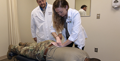 Chiropractor and student intern performing an adjustment on a member of the military.
