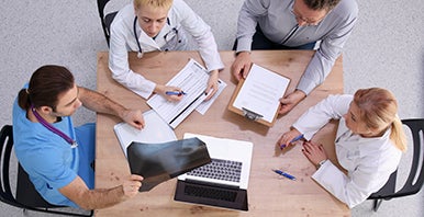 Four people around a table with laptops