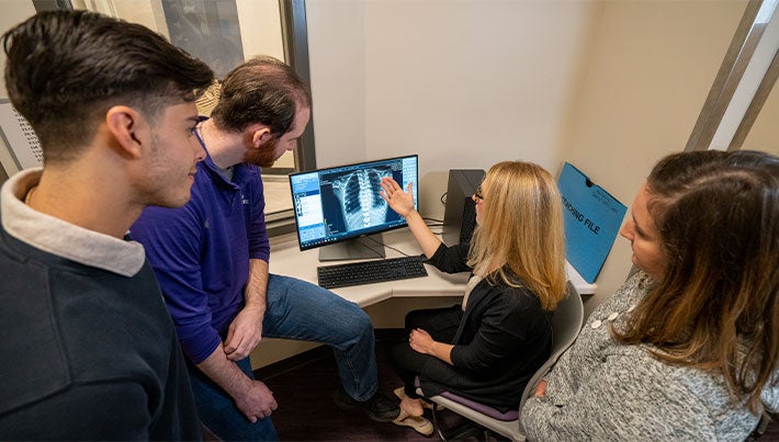 Four students reviewing an X-ray on computer screen.