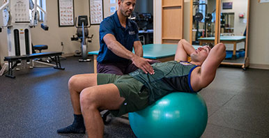 Chiropractor with a patient who is laying on a medicine ball.