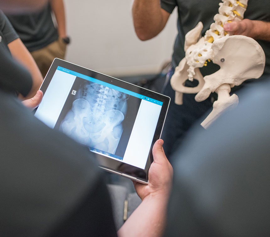 students reviewing X-ray on iPad against spine model.