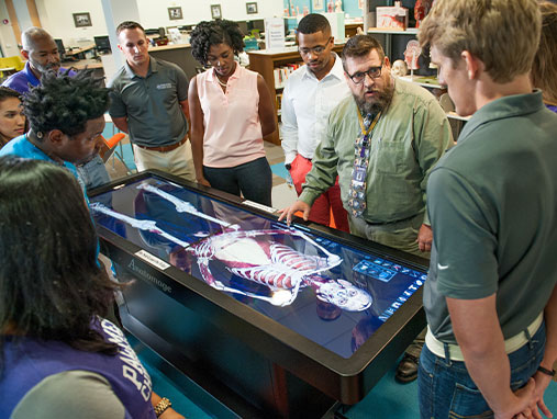 Instructor speaking to students next to anatomage table.