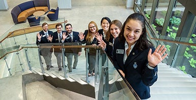 Campus guides in blazers ascending brightly lit staircase