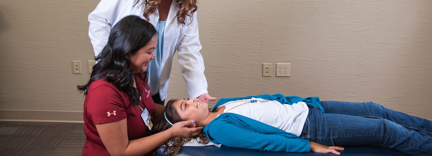 Chiropractor guiding student in delivering an adjustment.