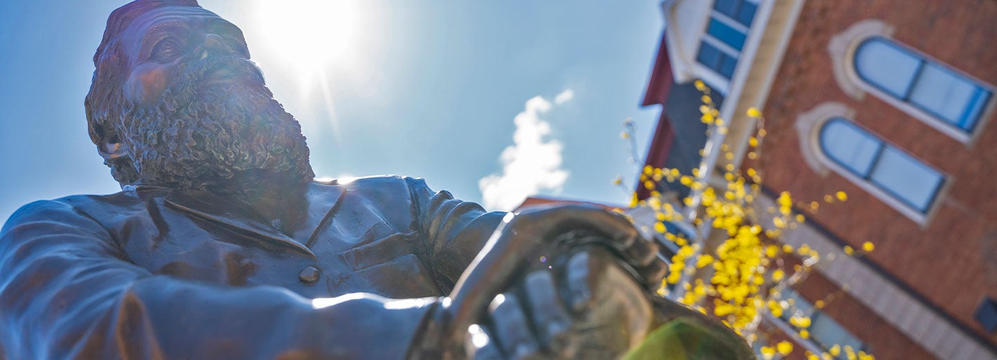 Sun streaming behind First Adjustment Statue of D.D. Palmer.