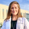 Kayla Gloisten in a white clinic coat in front of VA building.