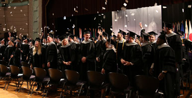 group of students in graduation gowns throwing cards into the air