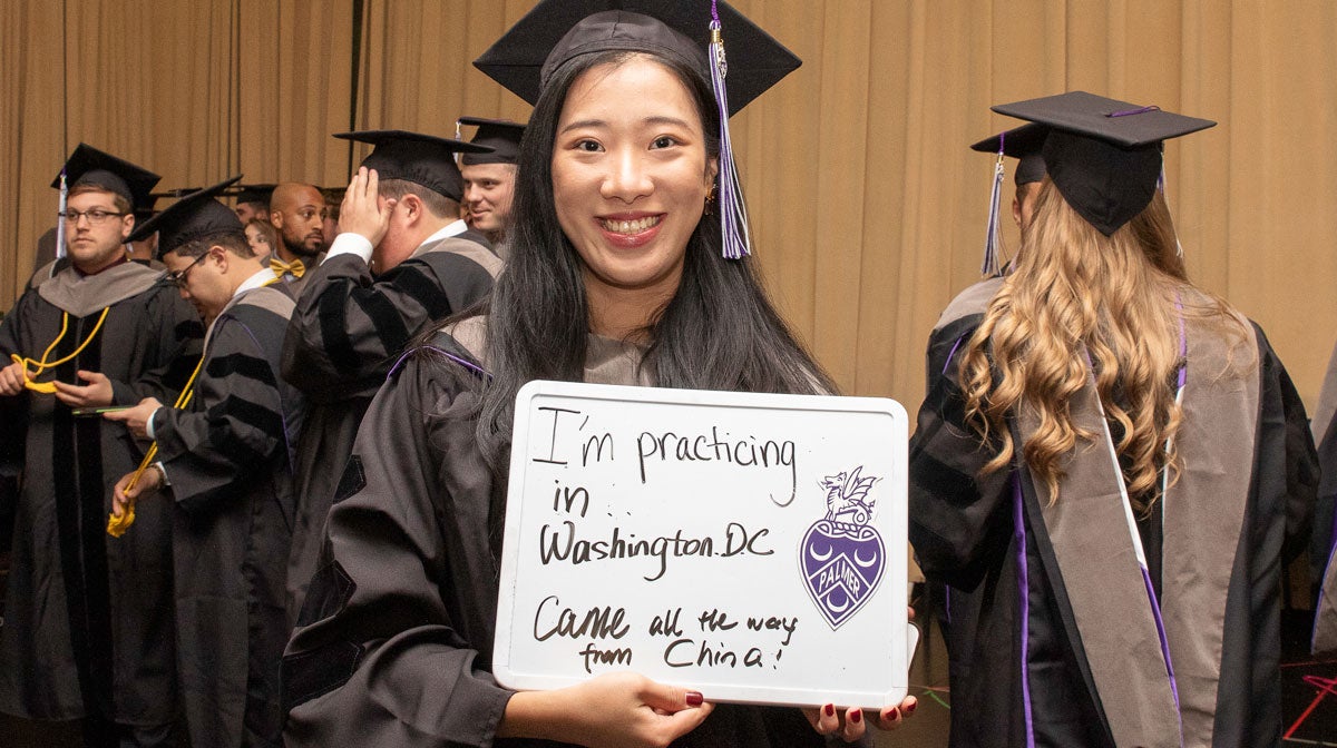 Student in graduation cap and gown with sign 