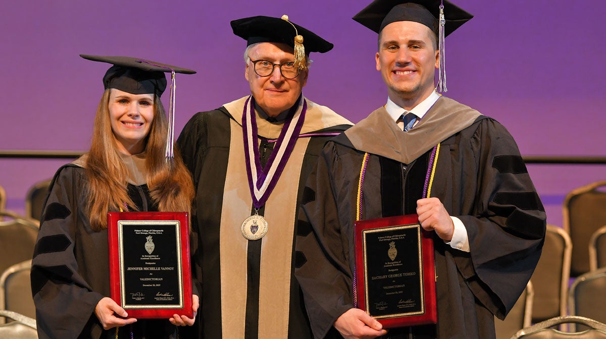 Two graduating students posing with awards with Dr. Martin.