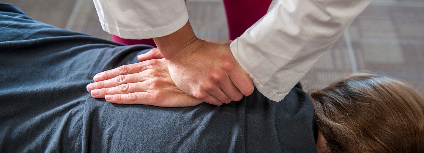 Hands on patient's upper back.