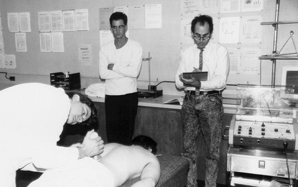 Black and white photo of doctors observing a patient's back.