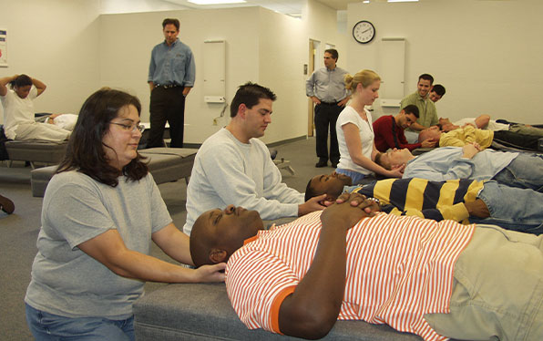 Chiropractic students learning how to perform an adjustment in a classroom