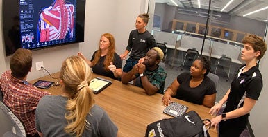 Group of students studying, looking at a computer monitor