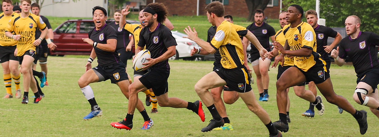 Men's rugby team in black uniforms playing against Nashville rugby team in yellow uniforms.