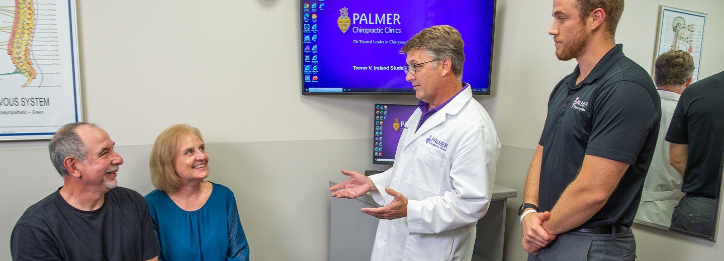 Chiropractor consulting with two patients.