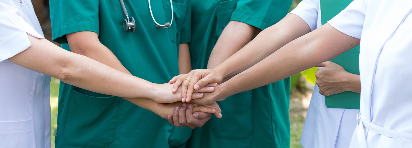 Group of nurses in scrubs with hands together