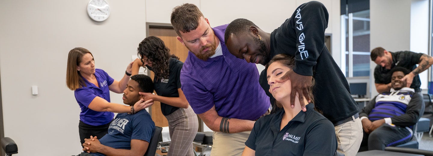 students practicing hand placement on patients with faculty overseeing