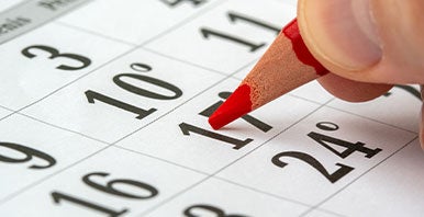 Red pencil marking off dates on a calendar.