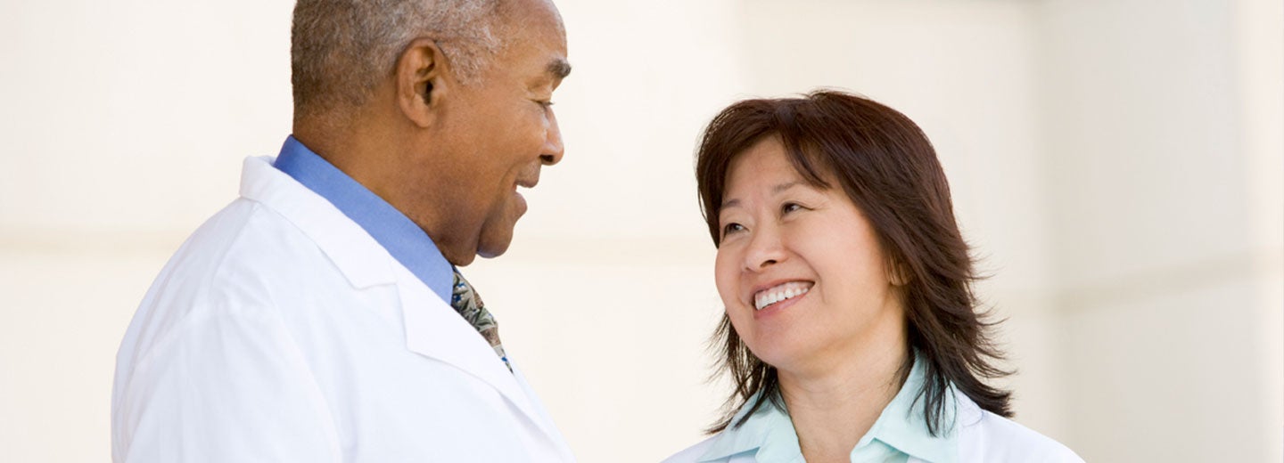 Two adults in white clinic coats smiling