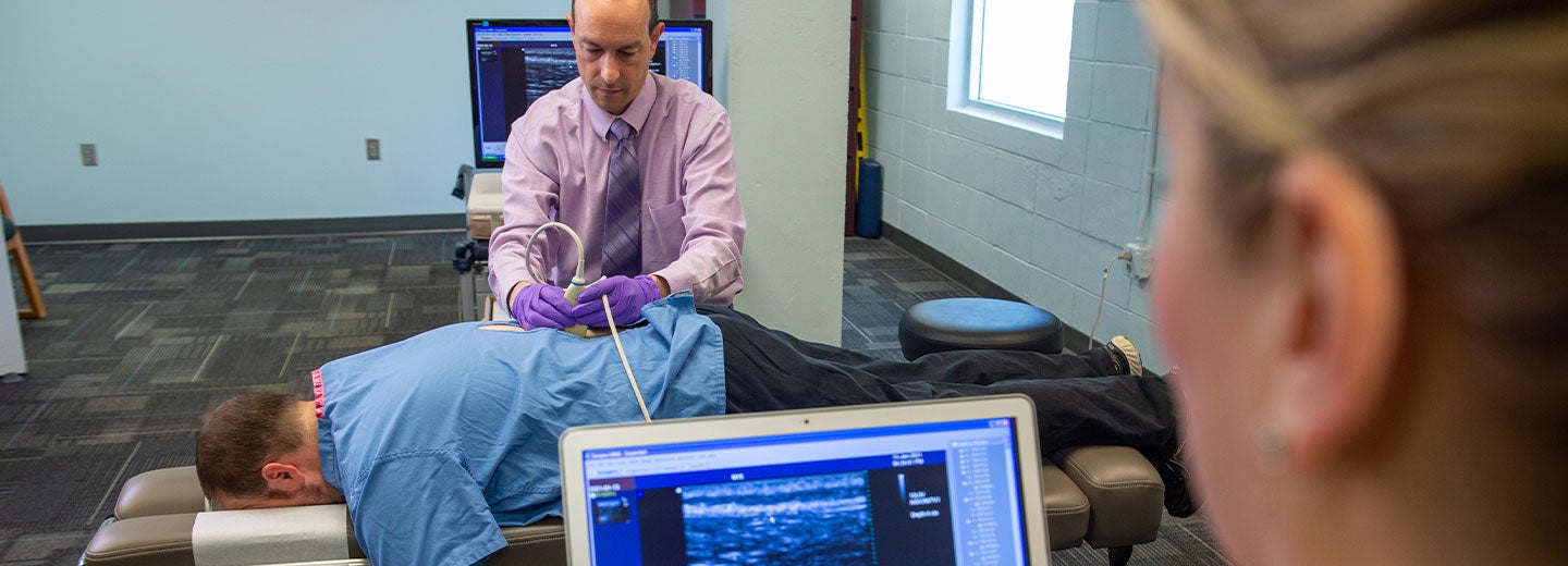 Two chiropractic researchers performing an ultrasound on a subject's back.