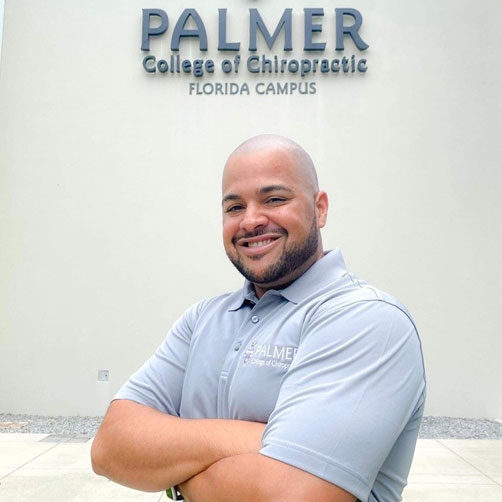 Carlos Bonilla smiling in front of Palmer Florida's building.