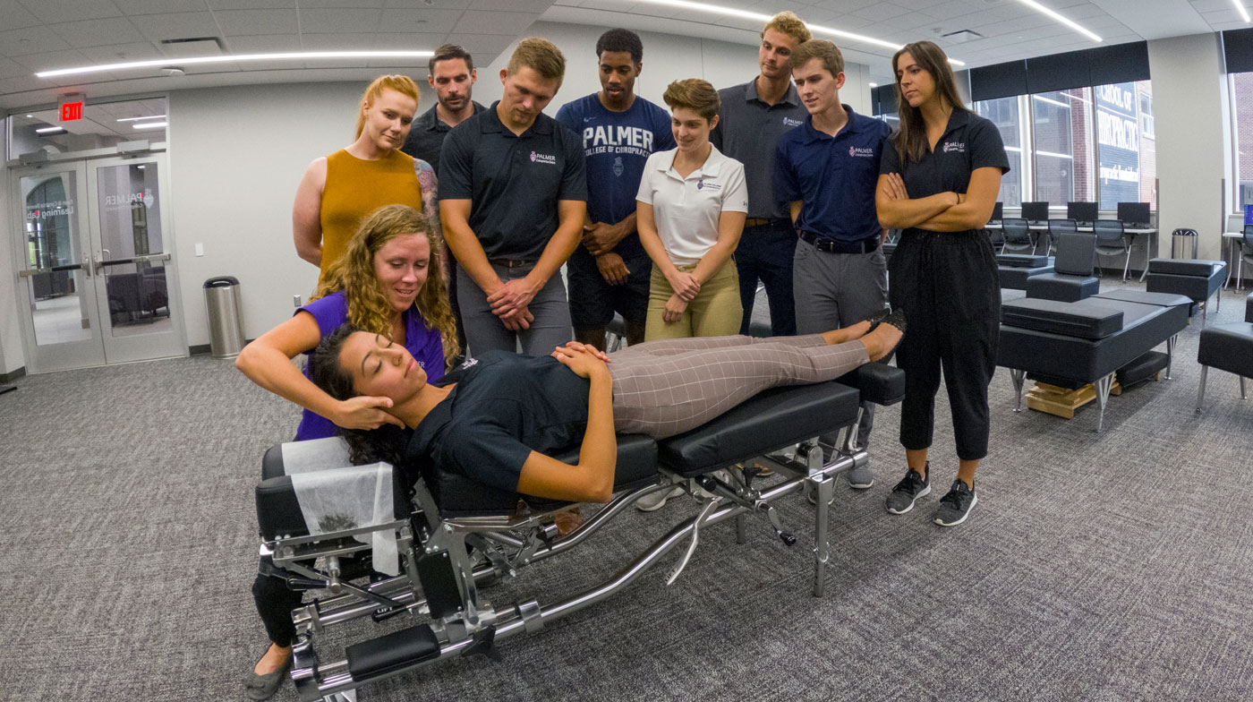 Chiropractic students observe a professor demonstrating an adjustment technique.
