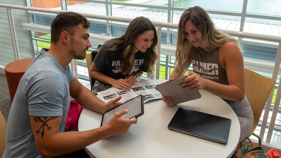 three students reviewing information on iPads