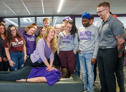 Group of students observing instructor's hand technique on patient's back.