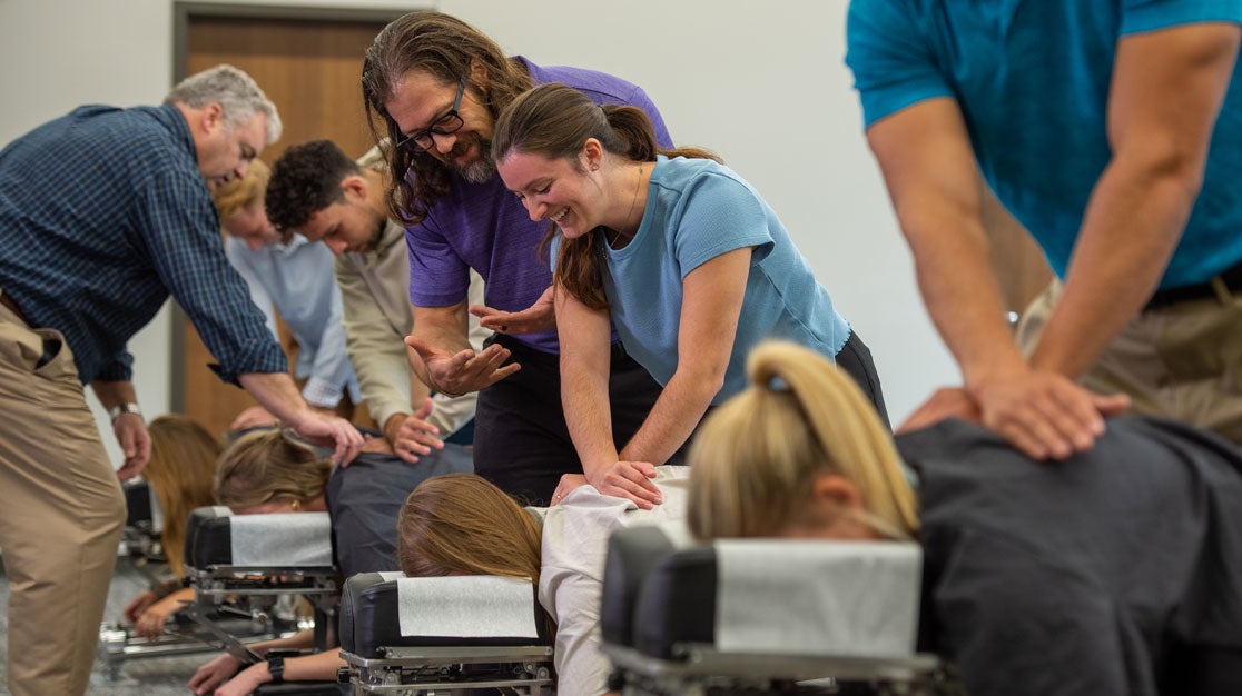 Instructor overseeing student adjusting client in Technique Lab.