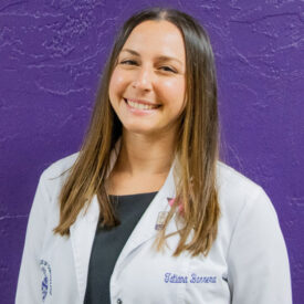 Tatiana Barrera in white clinic coat in front of purple wall