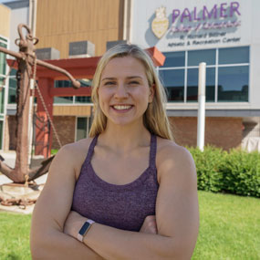 Catherine Kravets with arms crossed in front of Palmer Bittner Center