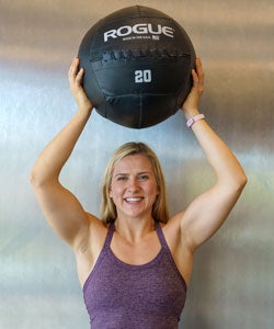 Catherine Kravets holding weight ball above her head.