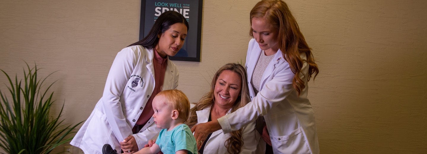 Clinic doctor and intern examining child's back