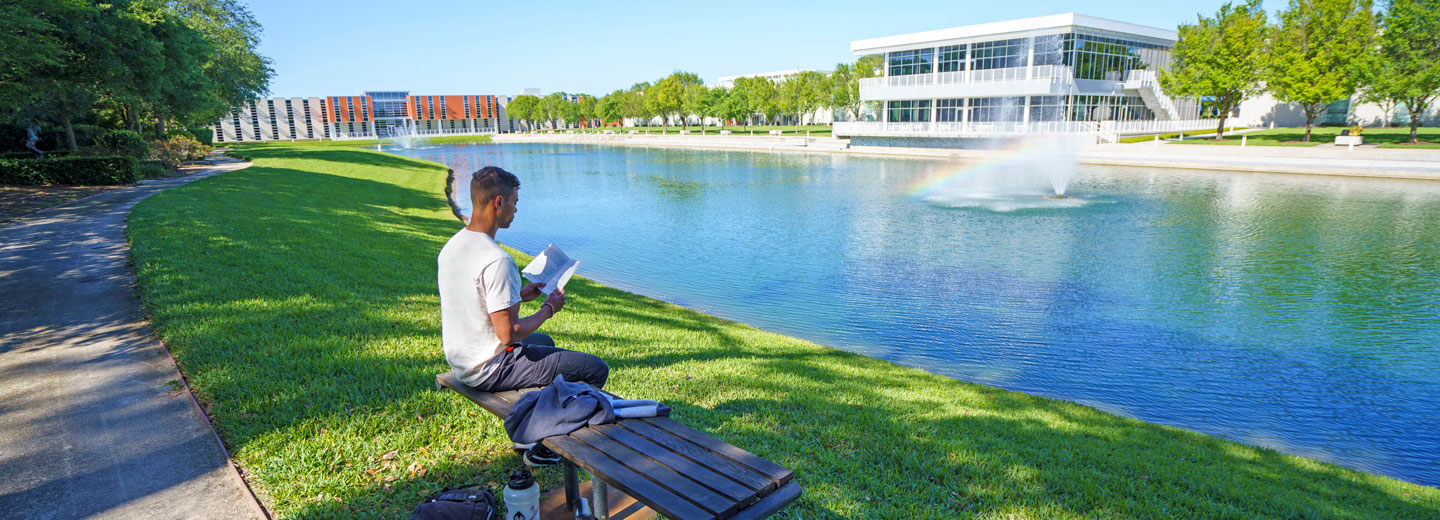 Student reading book by Palmer Florida campus fountains