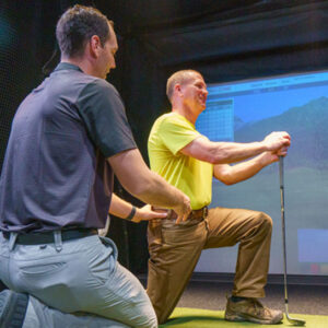 Dr. Buns helping golfer stretch at golf simulator.